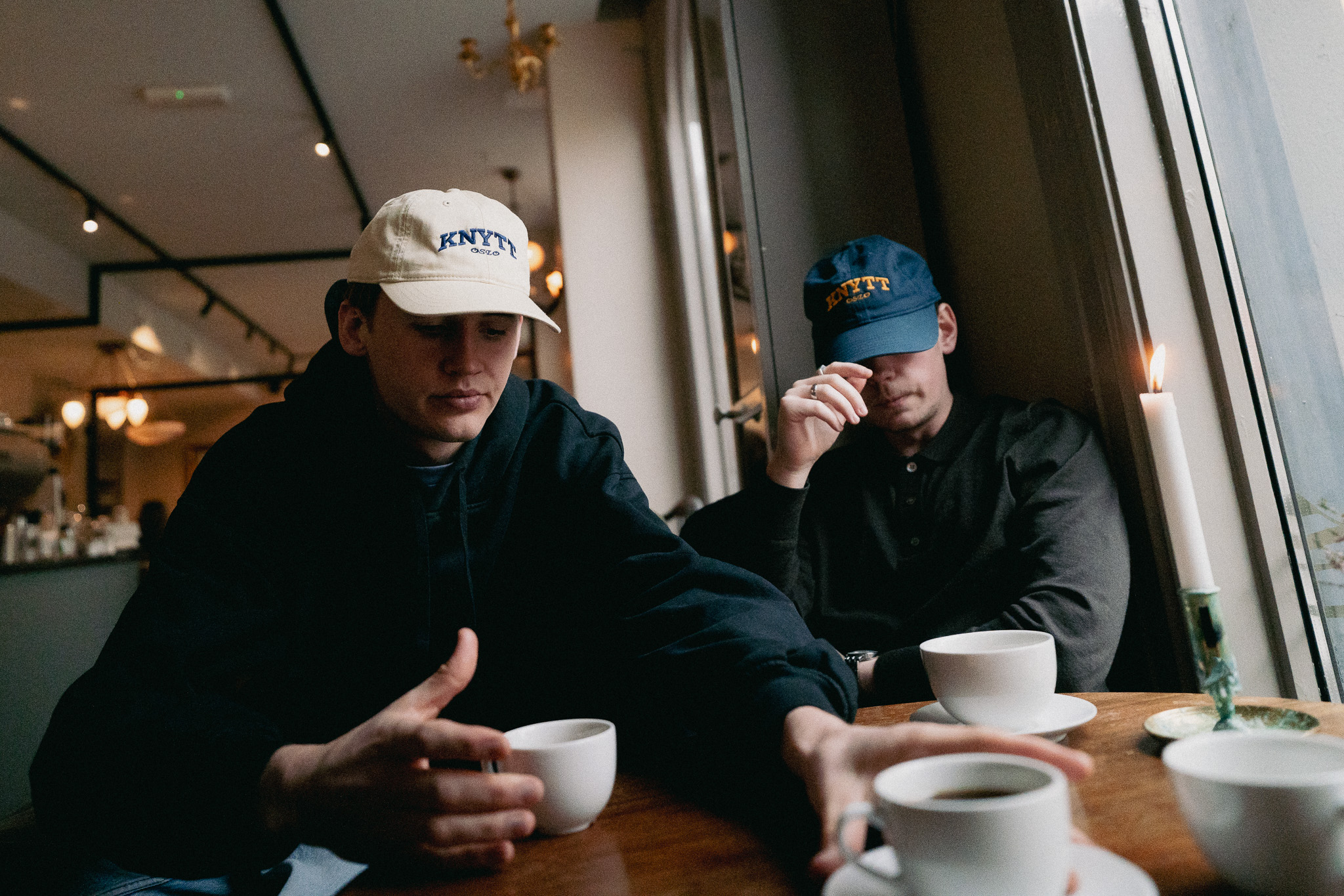 To studenter i Knytt-capser over en kopp kaffe.
